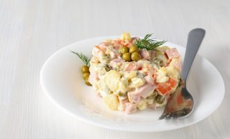 Салат Оливье с колбасой на тарелке