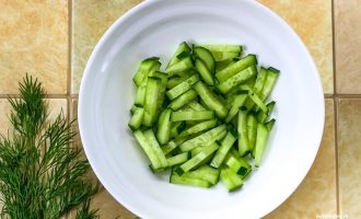 Нарезанные брусочками свежие огурцы в тарелке.
