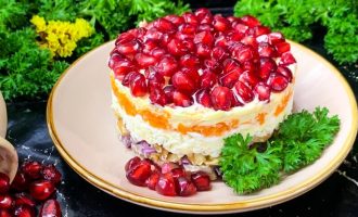 Готовый мясной салат с гранатом и грецким орехом, подача на тарелке.
