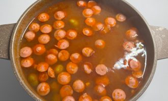 Суп с овощами, курицей и сосисками в кастрюле