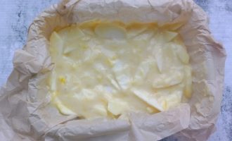 Форма с пергаментом, заполненная тестом с яблоками