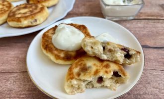 Сырники с вяленой клюквой и сметаной на тарелке