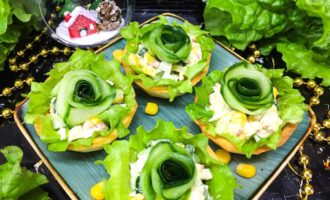 Тарталетки с кукурузой, крабовыми палочками, яйцом и огуречной розой на листе салата на праздничной подаче