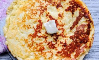 Готовый ленивый хачапури на сковороде с кусочком сливочного масла