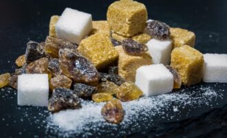 Белый и коричневый сахар в кубиках и кристаллах на темном фоне