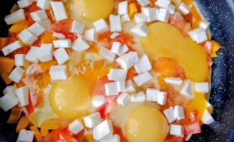 Яичница с овощами и кусочками брынзы на сковороде